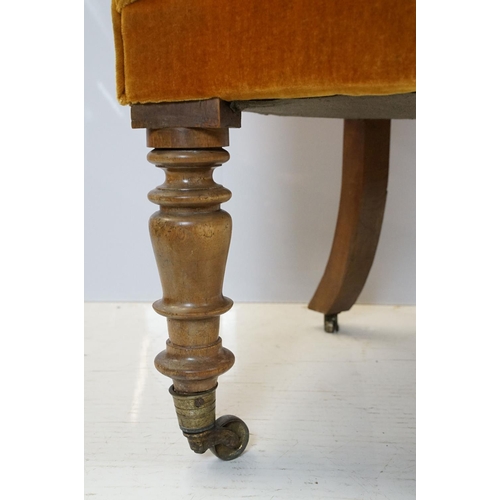 654 - Early 20th century wing back armchair of curved form, with button back, upholstered in orange, on tu... 