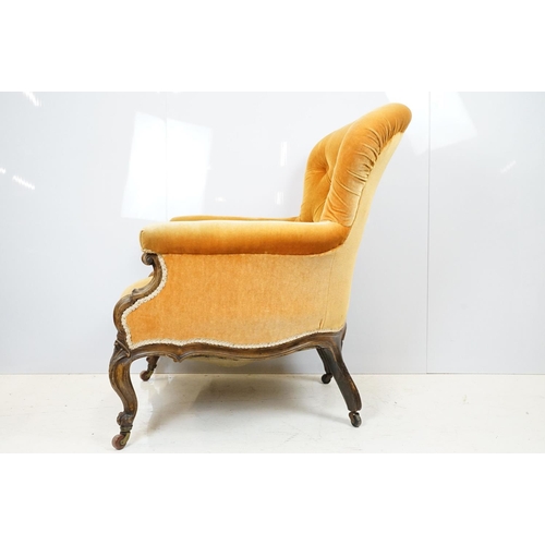 654 - Early 20th century wing back armchair of curved form, with button back, upholstered in orange, on tu... 