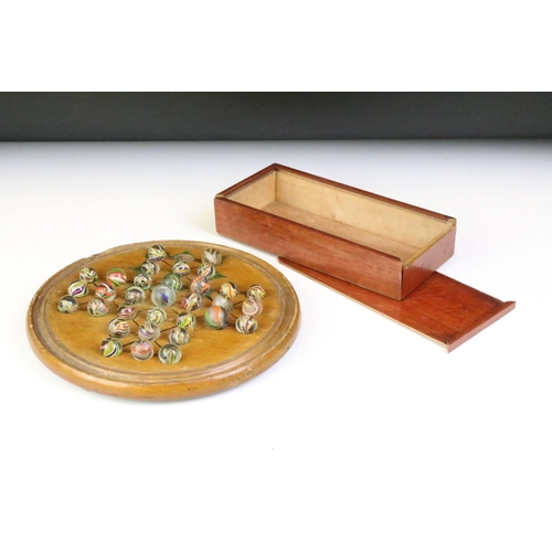 234 - An antique carved wooden solitaire board complete with antique marbles.