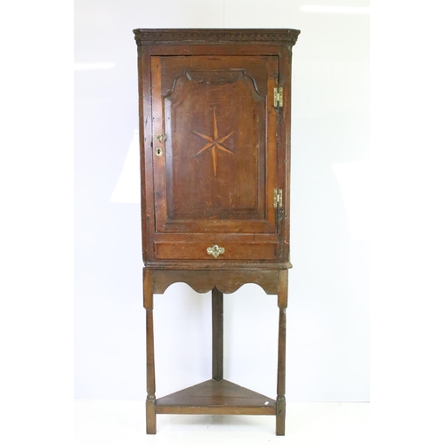 697 - Georgian oak corner cupboard, with dentil cornice above panelled door with parquetry geometric star ... 