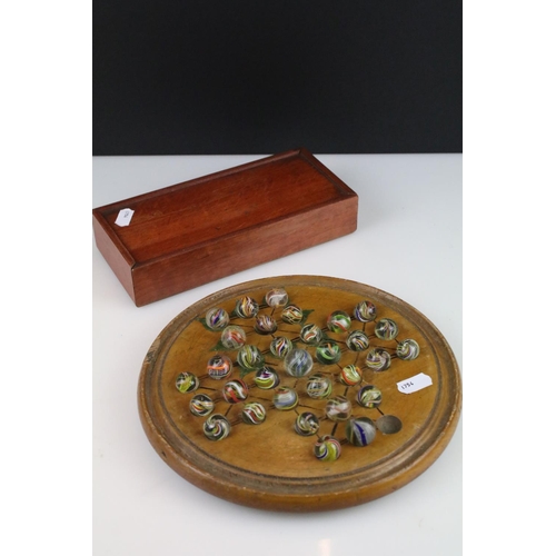 234 - An antique carved wooden solitaire board complete with antique marbles.