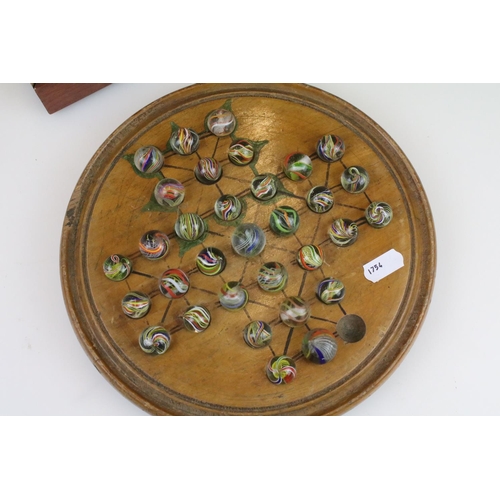 234 - An antique carved wooden solitaire board complete with antique marbles.