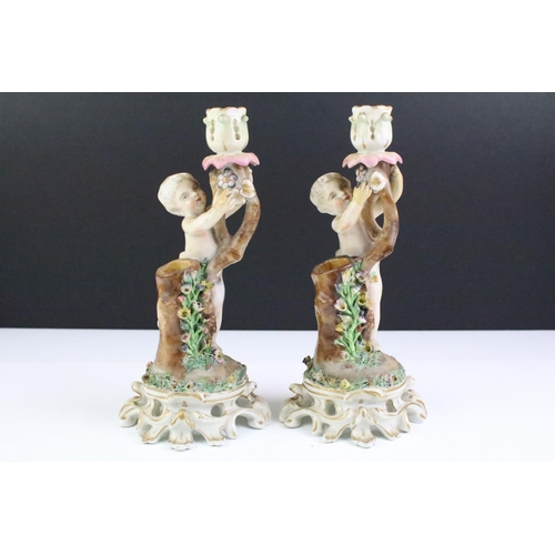 12 - Pair of 19th century Continental porcelain candlesticks modelled with putti, with blue crossed sword... 