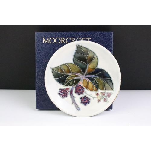 86 - Two boxed Moorcroft pottery pin dishes to include a Bramble Pattern and green ground floral example,... 