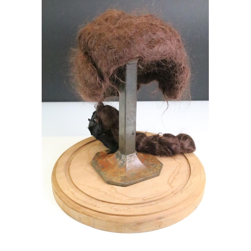 167 - 19th Century wig on an antique cast metal stand housed within a glass cloche raised on a wooden base... 