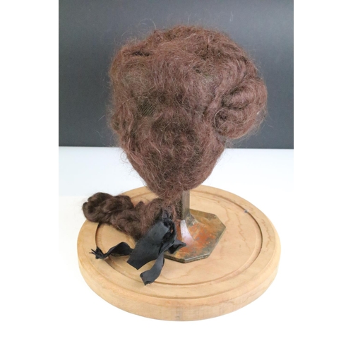 167 - 19th Century wig on an antique cast metal stand housed within a glass cloche raised on a wooden base... 