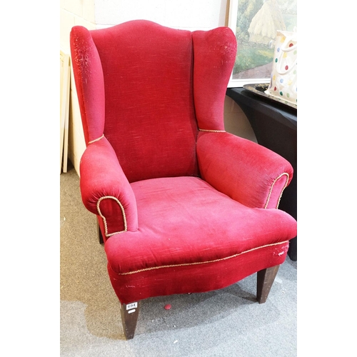 694 - 20th Century red velvet wing backed arm chair raised on tapering oak legs. Measures 102 x 82cm.