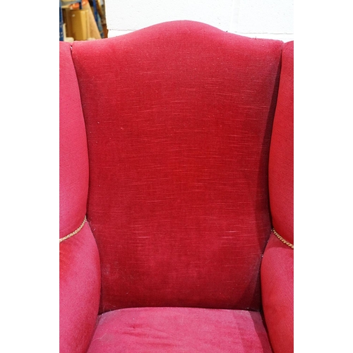 694 - 20th Century red velvet wing backed arm chair raised on tapering oak legs. Measures 102 x 82cm.