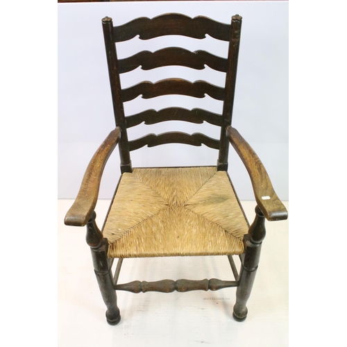 654 - Set of five oak ladder back chairs, including one chair with arms, all with rush seats