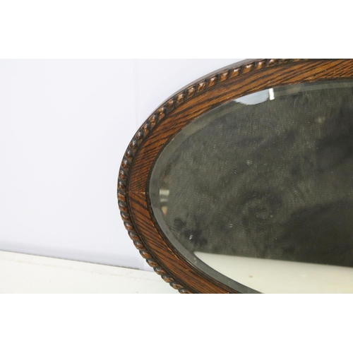 676 - Carved oak oval mirror with bevelled plate, 77 x 49cm