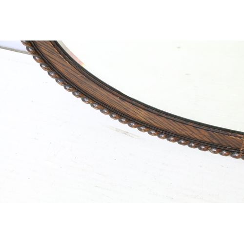 676 - Carved oak oval mirror with bevelled plate, 77 x 49cm