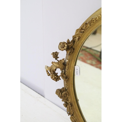 707 - Oval gilt mirror moulded with flowers, berries and leaves, 67 x 38cm