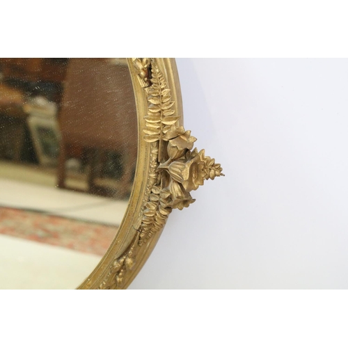 707 - Oval gilt mirror moulded with flowers, berries and leaves, 67 x 38cm