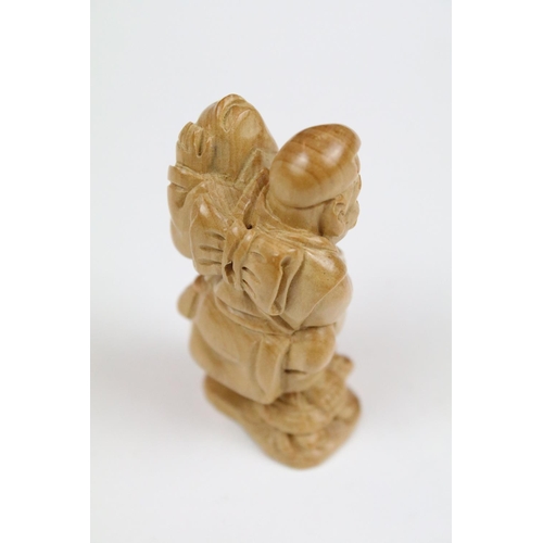 289 - Two Chinese carved wooden netsuke to include a figure of an oriental man holding fish.