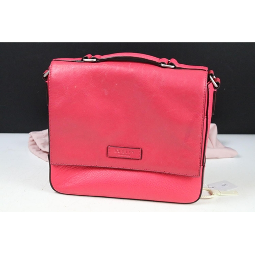 394 - Two Radley handbags to include a black leather handbag and a pink example, both housed within pink R... 