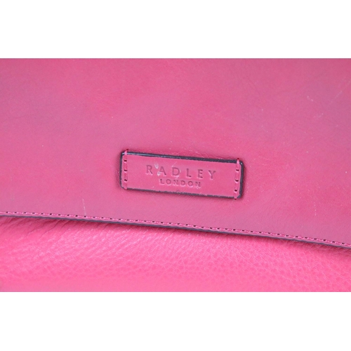 394 - Two Radley handbags to include a black leather handbag and a pink example, both housed within pink R... 