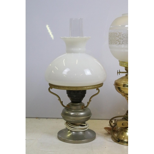 397 - Group of four 20th century oil lamps, three converted to electric, the other being a brass oil lamp ... 