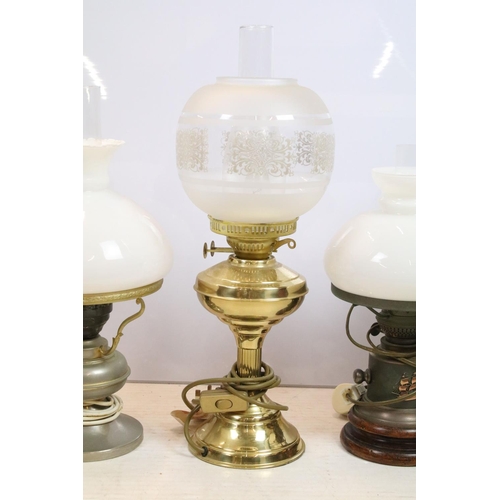 397 - Group of four 20th century oil lamps, three converted to electric, the other being a brass oil lamp ... 