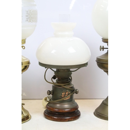 397 - Group of four 20th century oil lamps, three converted to electric, the other being a brass oil lamp ... 