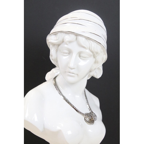 456 - Ceramic bust of a female with pensive expression, wearing a silver necklace, raised on a marble effe... 