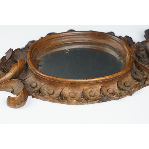 212 - An antique carved wooden Black Forest hand mirror with foliate decoration.