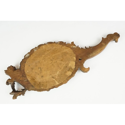 212 - An antique carved wooden Black Forest hand mirror with foliate decoration.