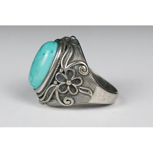 222 - A silver ladies dress ring with central turquoise cabochon and floral decoration, marked 925 to the ... 