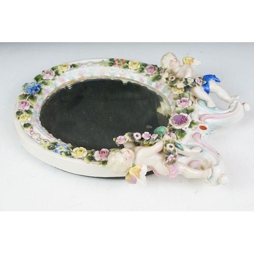 41 - Continental porcelain floral encrusted wall mirror with bevelled glass and two putti to base, hand p... 