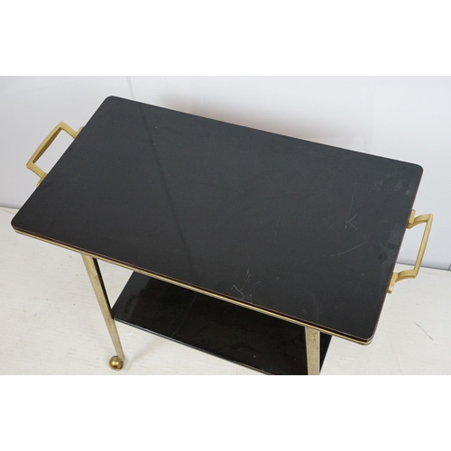 694 - Mid century black and gold two tier trolley table , 70cm high x 81cm wide x 40cm deep