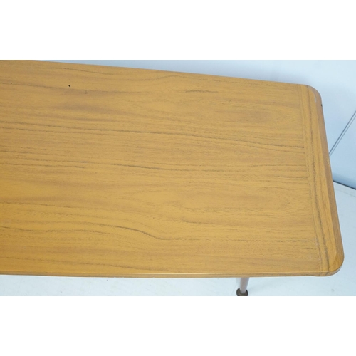 743 - Mid century coffee table with rack to underside on tapering legs with metal feet, 35cm high x 107cm ... 