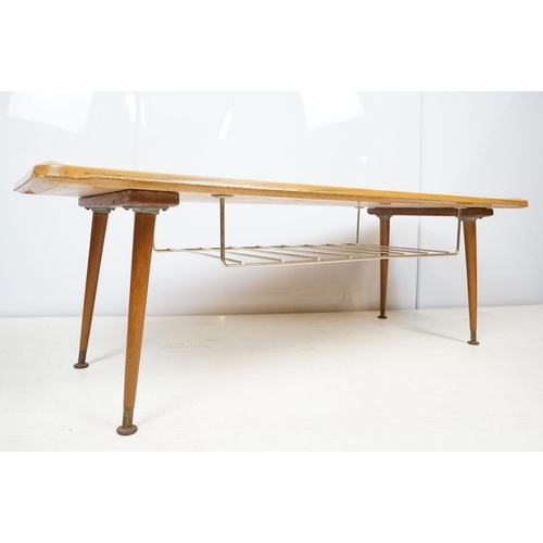 743 - Mid century coffee table with rack to underside on tapering legs with metal feet, 35cm high x 107cm ... 