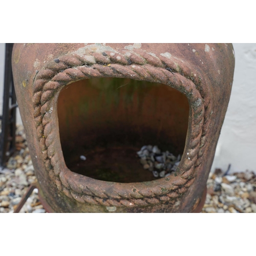 627 - Terracotta patio chimenea, raised on three scrolled wrought iron supports, approx 109cm tall