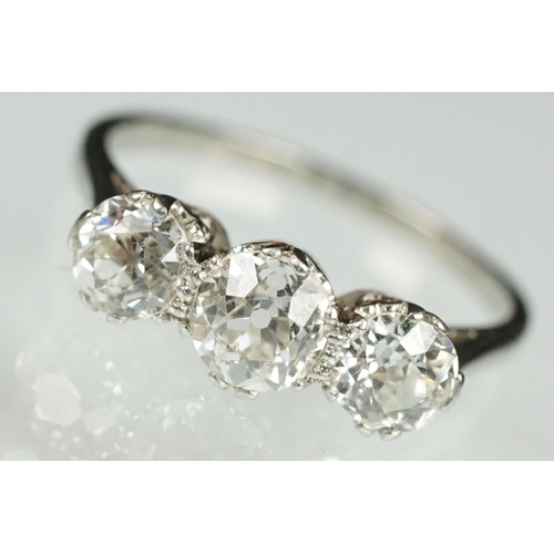 3 - Three stone diamond and platinum ring. The ring being set with three round old cut diamonds in prong... 