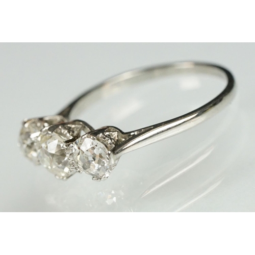 3 - Three stone diamond and platinum ring. The ring being set with three round old cut diamonds in prong... 