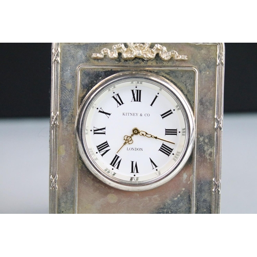 369 - Kitney & Co silver fronted easel back clock timepiece having a round face with roman numerals to the... 