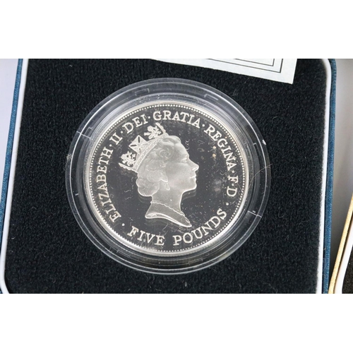 64 - A collection of four Royal Mint silver proof crown coins all encapsulated within display cases.