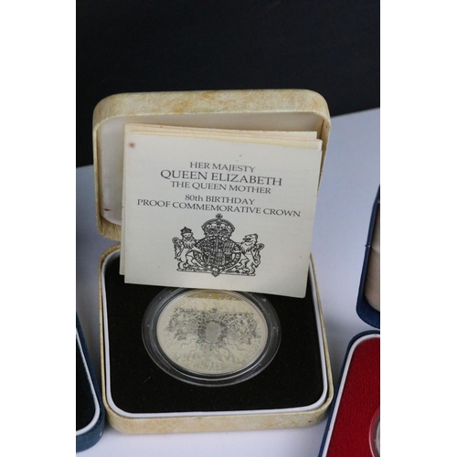 64 - A collection of four Royal Mint silver proof crown coins all encapsulated within display cases.