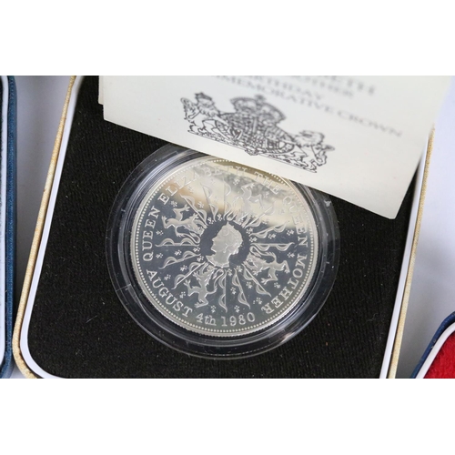 64 - A collection of four Royal Mint silver proof crown coins all encapsulated within display cases.