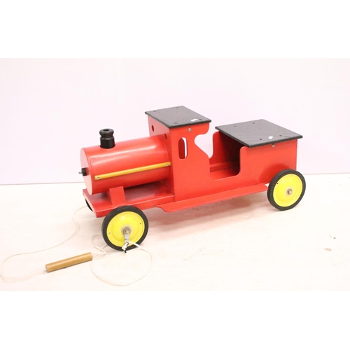489 - Painted wooden model of a train, raised on four wheels with metal hubs, approx 73cm long