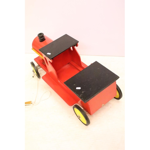 489 - Painted wooden model of a train, raised on four wheels with metal hubs, approx 73cm long