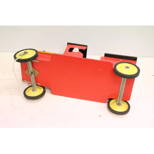 489 - Painted wooden model of a train, raised on four wheels with metal hubs, approx 73cm long