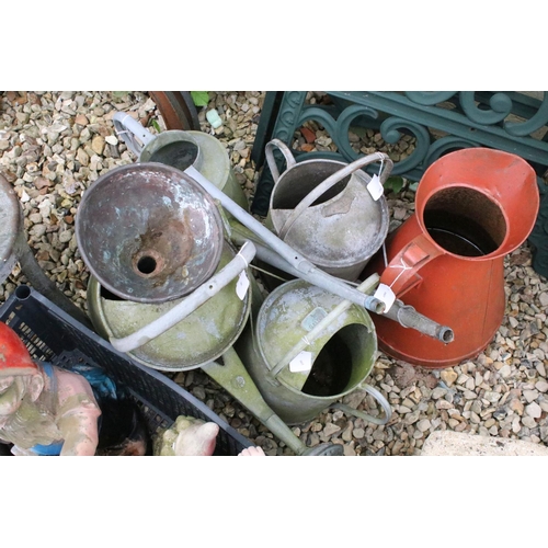 527 - Four metal watering cans together with a jug, metal stall, and a group of garden ornaments to includ... 