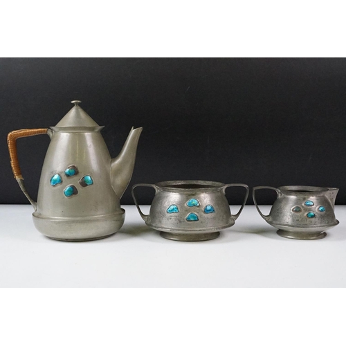 254 - An early twentieth century pewter tea set with peacock enamel decoration in the style of archibald k... 