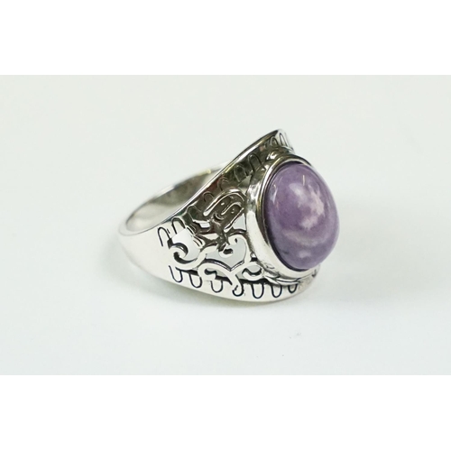305 - A 925 sterling silver ladies ring with purple cabochon central stone with decorative shoulder work, ... 