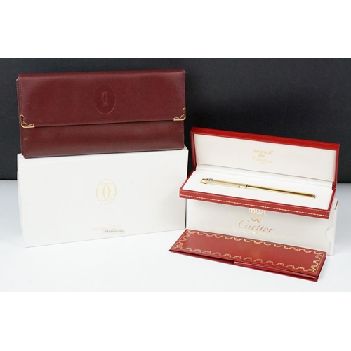 242 - A boxed Cartier leather purse together with a boxed Cartier pen, both with original display boxes.