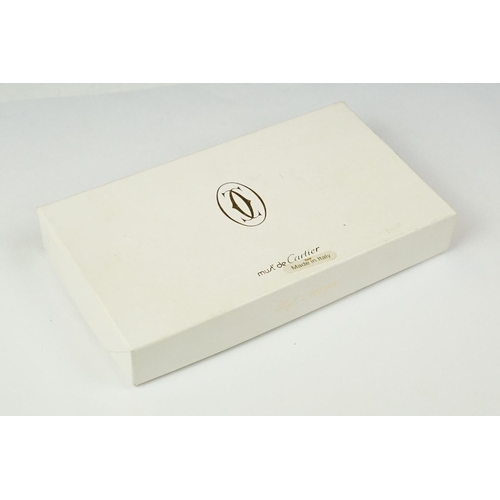 242 - A boxed Cartier leather purse together with a boxed Cartier pen, both with original display boxes.