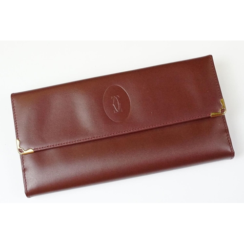 242 - A boxed Cartier leather purse together with a boxed Cartier pen, both with original display boxes.