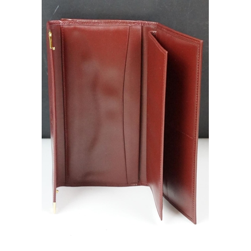 242 - A boxed Cartier leather purse together with a boxed Cartier pen, both with original display boxes.
