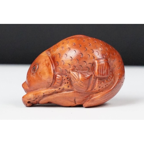 243 - Two carved oriental Netsuke in the form of a dog and a fish.