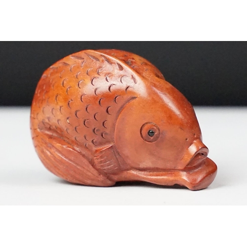 243 - Two carved oriental Netsuke in the form of a dog and a fish.